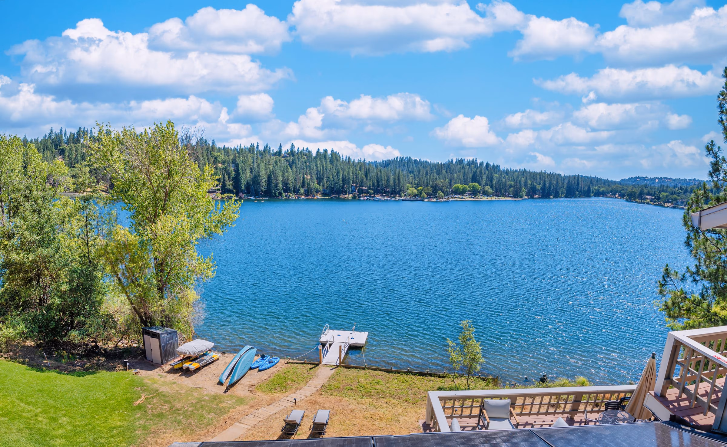 Panoramic view over Pine Mountain Lake from the property, with the private dock, a canoe and kayaks pulled up on the shoreline below and forested hills across the water