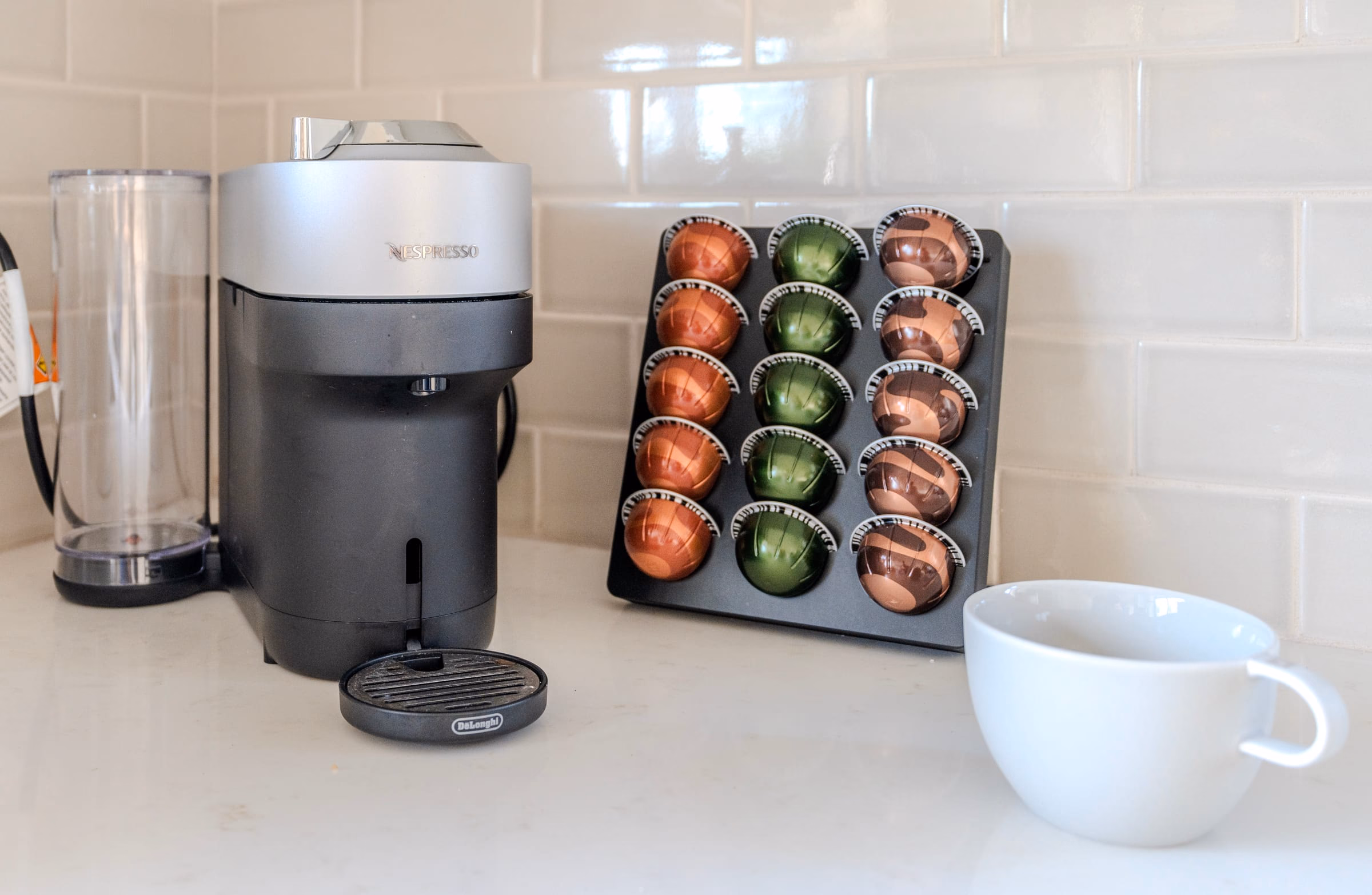 Nespresso machine, coffee capsules and a cup arranged on the kitchen counter