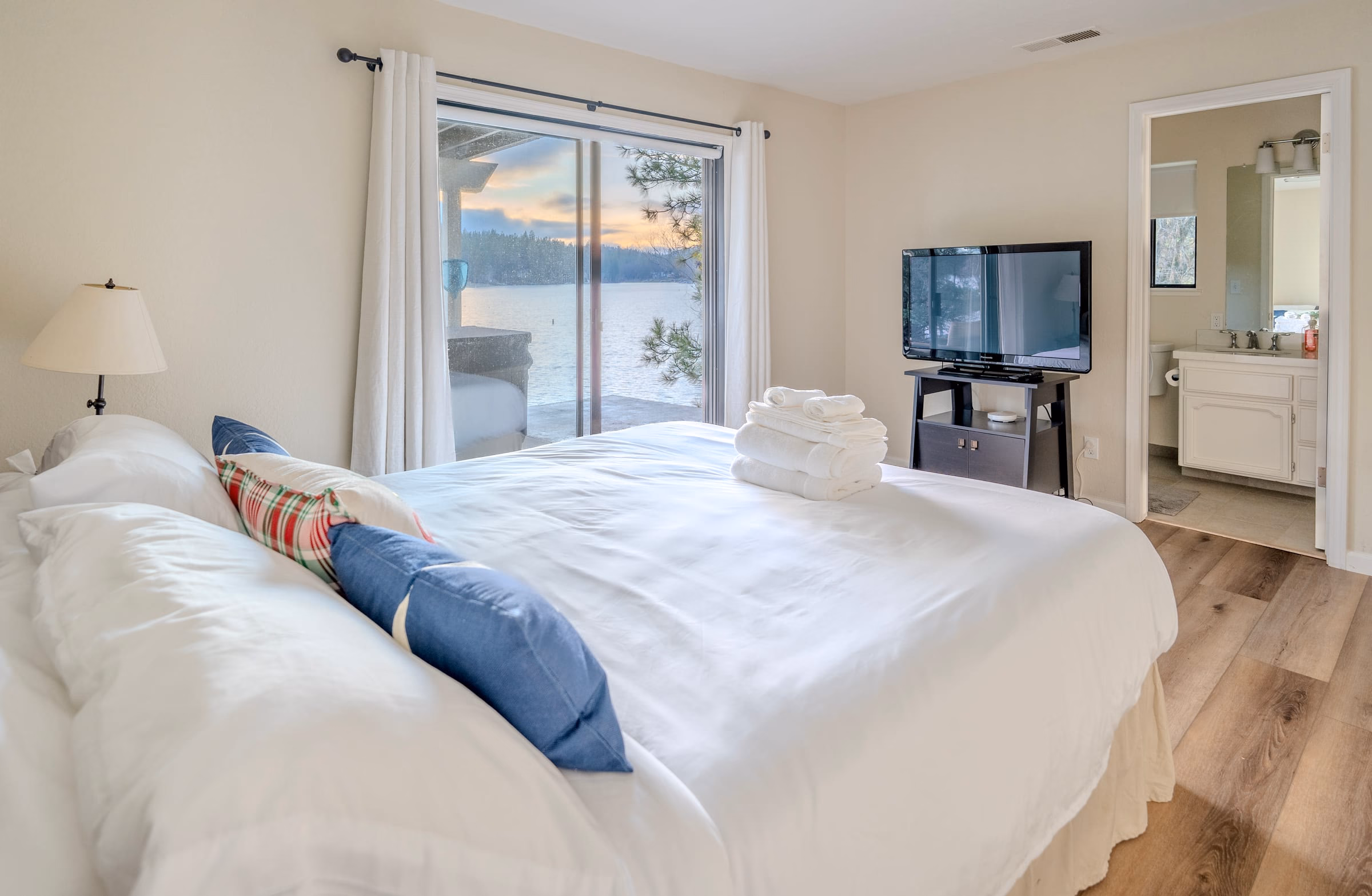 Bedroom with a large bed, lake view, television and an adjoining full bathroom