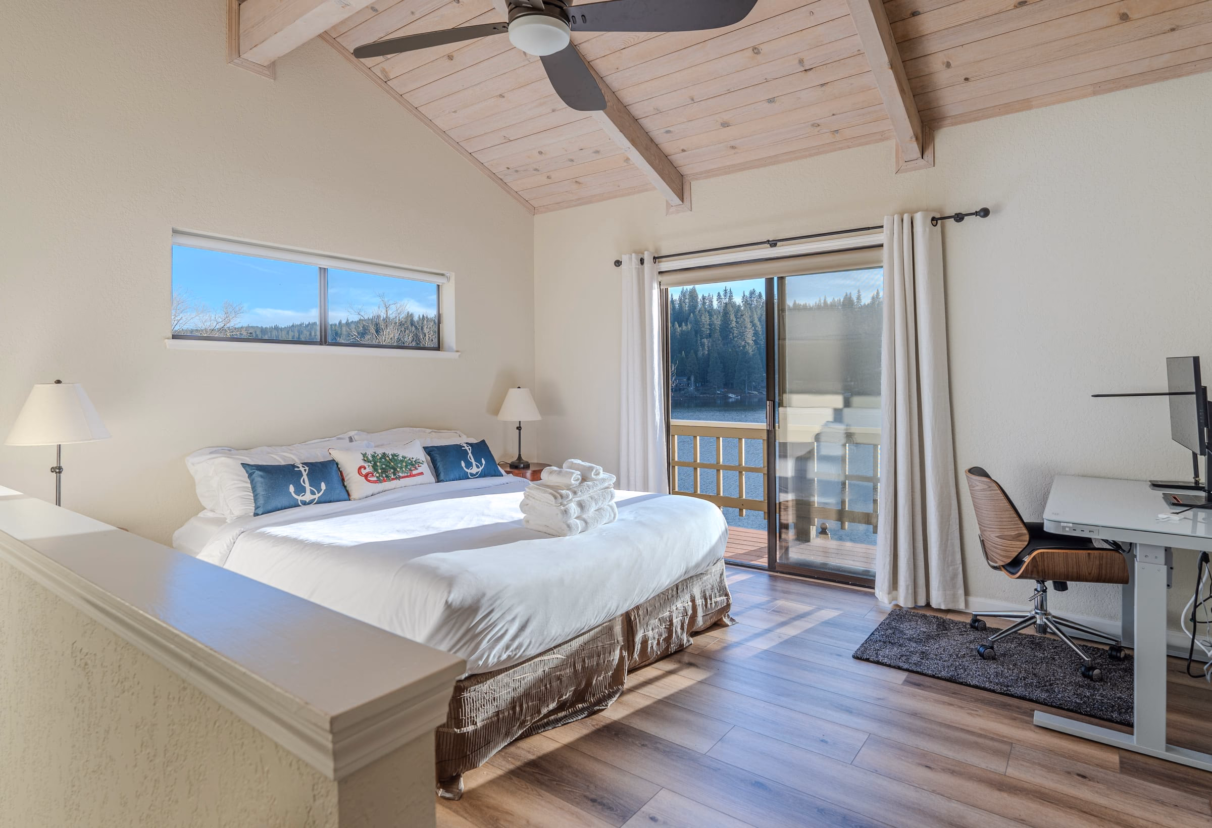 Lake-view bedroom with a large bed, vaulted wood ceiling, private balcony and adjustable desk