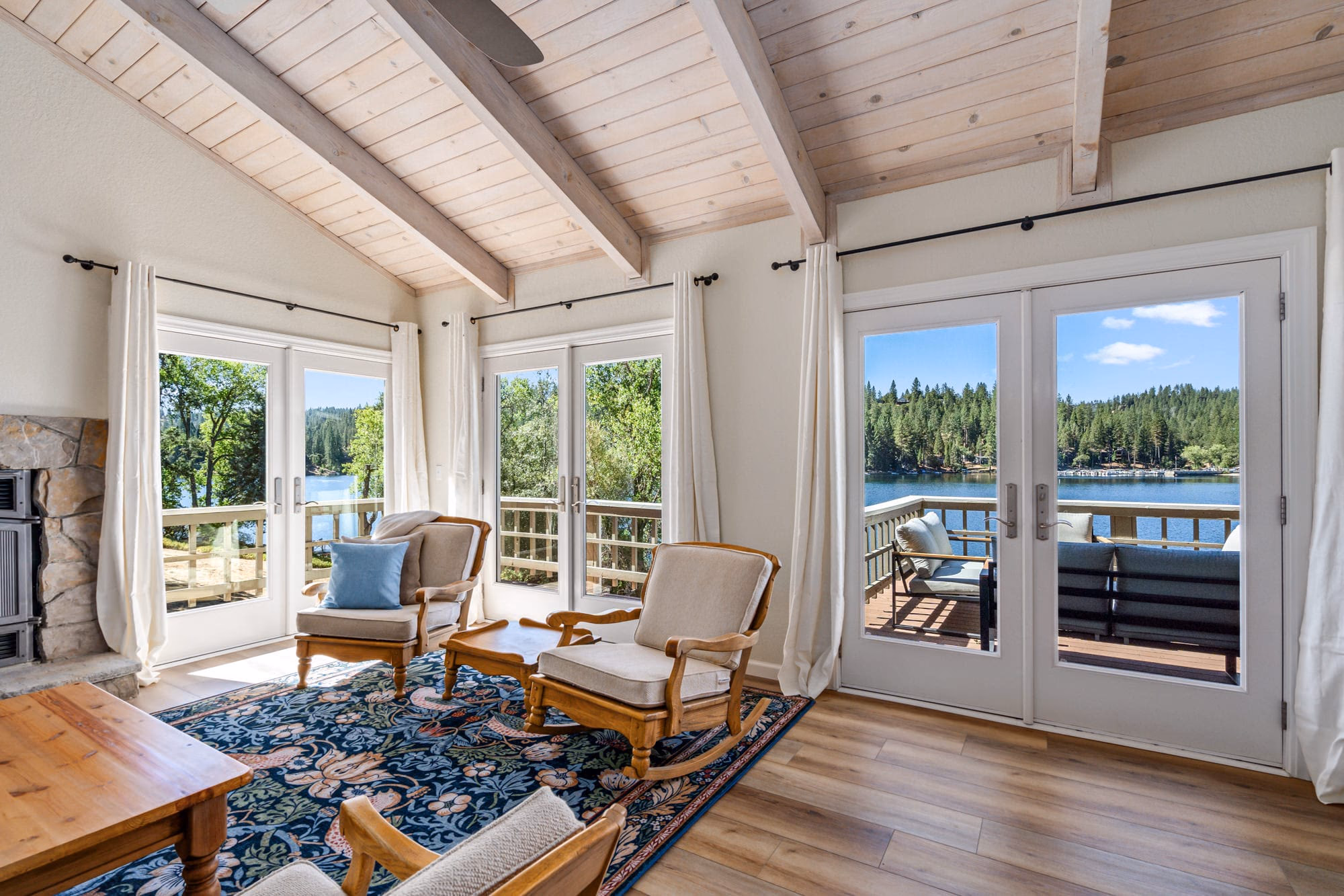 Living room seating surrounded by French doors with views of Pine Mountain Lake and the deck