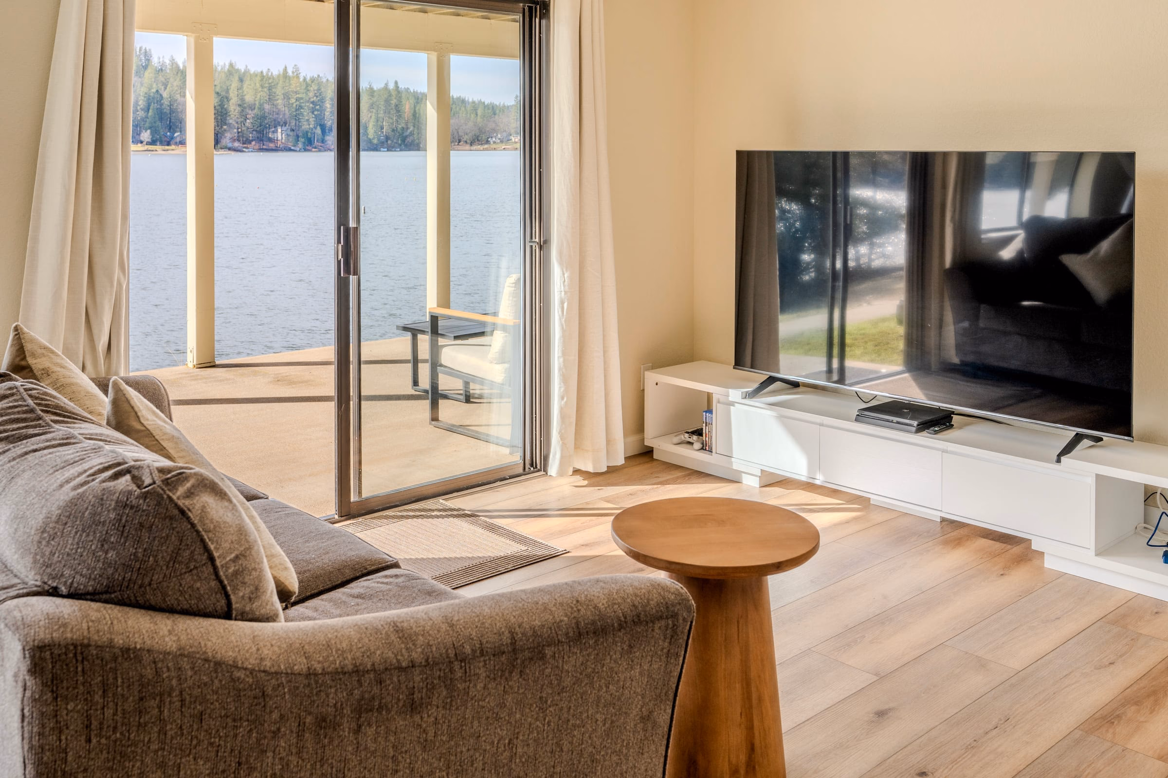 Lower living room with a sectional sofa, large television and sliding door opening to a covered lakefront patio